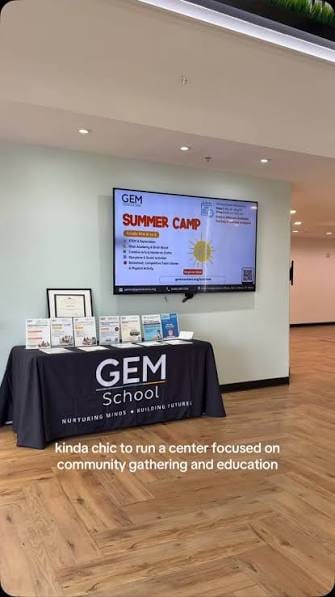 The lobby inside GEM Center, with a screen on the wall and a GEM School table.